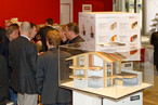Attraktion auf dem KRONO Stand: Das 3D-Modell des KRONOPLY Wohlfühlhauses. Der Würfel dahinter präsentiert die Systemaufbauten im Detail.